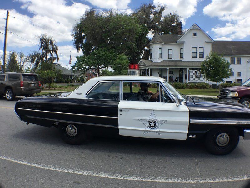 A black and white police car is parked in front of a white house
