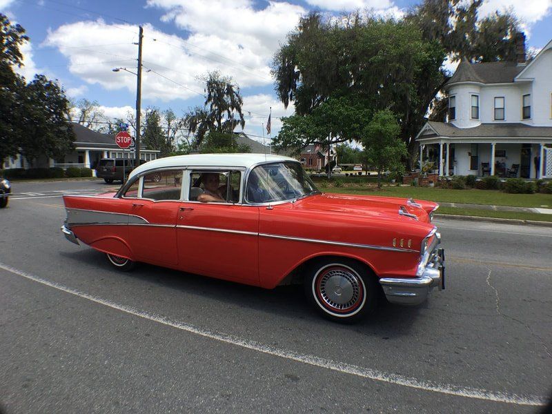 A red and white car is driving down a street