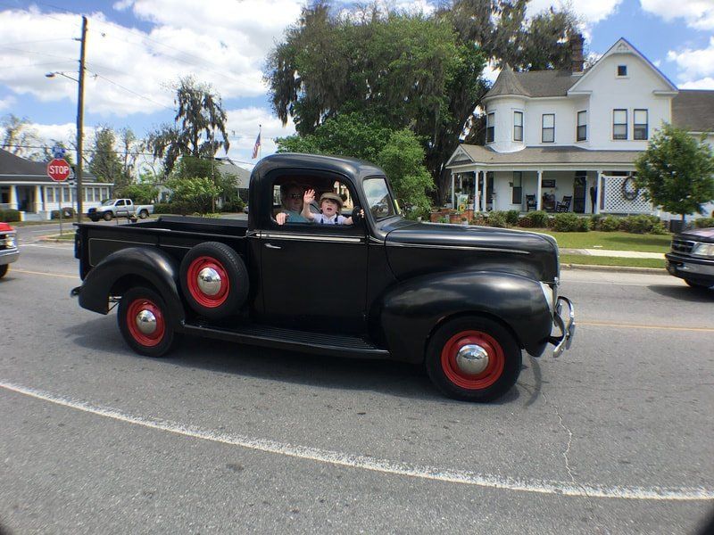 A black truck with red wheels is driving down a street