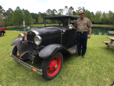 A man standing next to a black car with red wheels