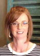 A woman wearing glasses and a striped shirt is smiling for the camera.