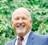 A man in a suit and tie is smiling for the camera.