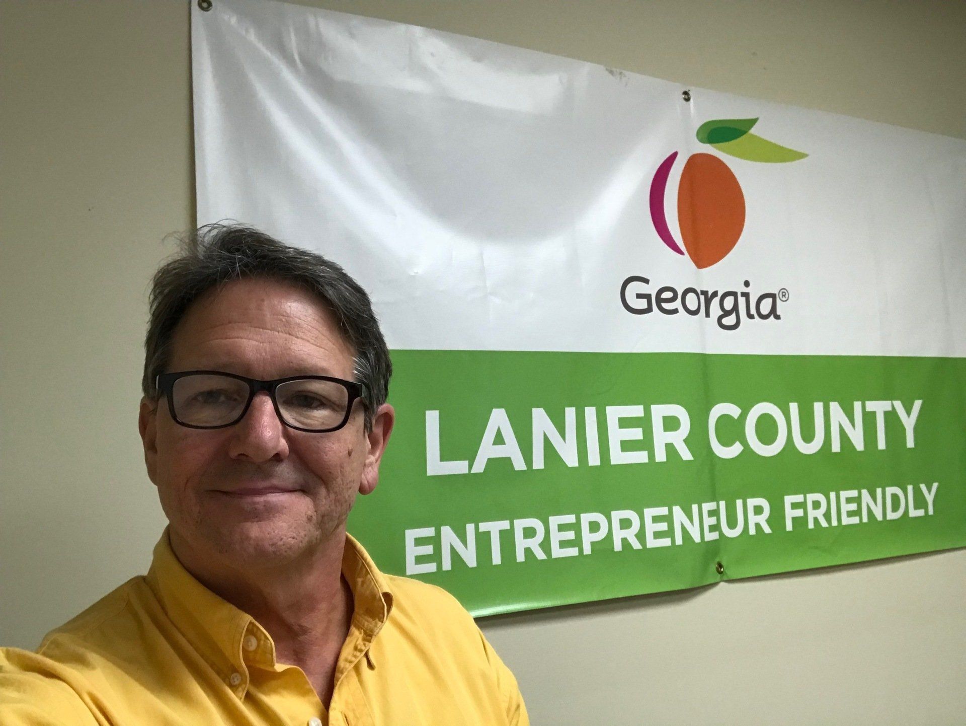 A man is standing in front of a sign that says georgia lanier county entrepreneur friendly