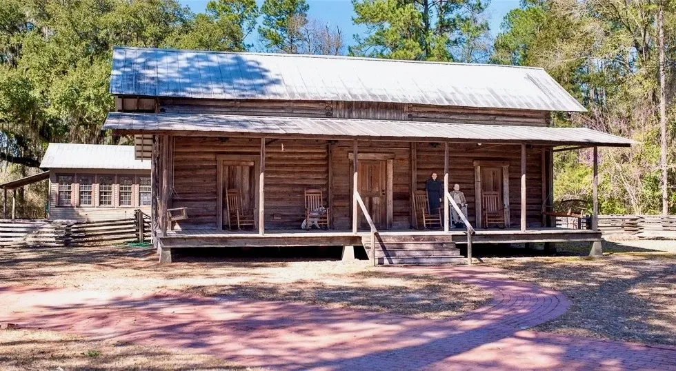 A log cabin with a porch in the middle of a forest.