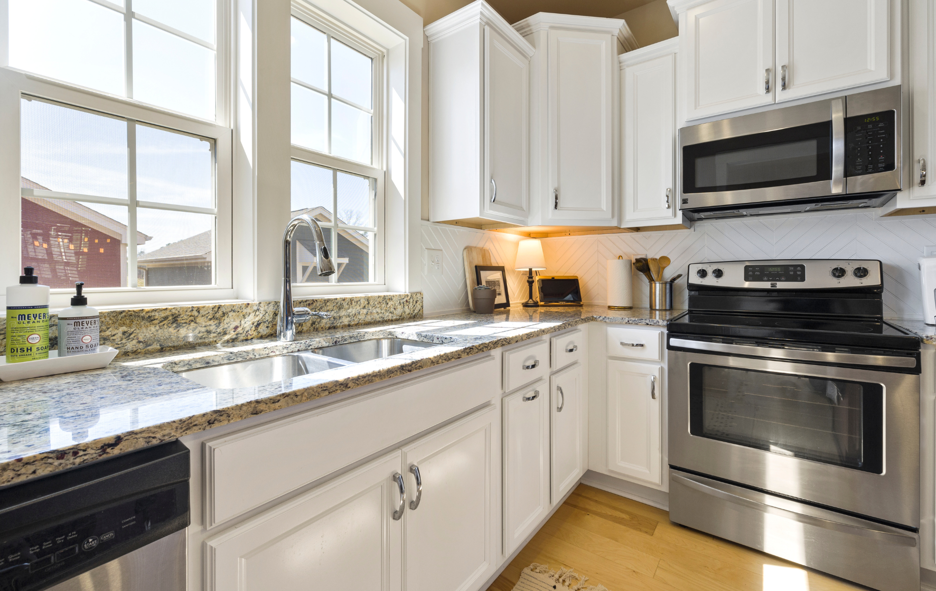 A kitchen with white cabinets , stainless steel appliances and granite counter tops.