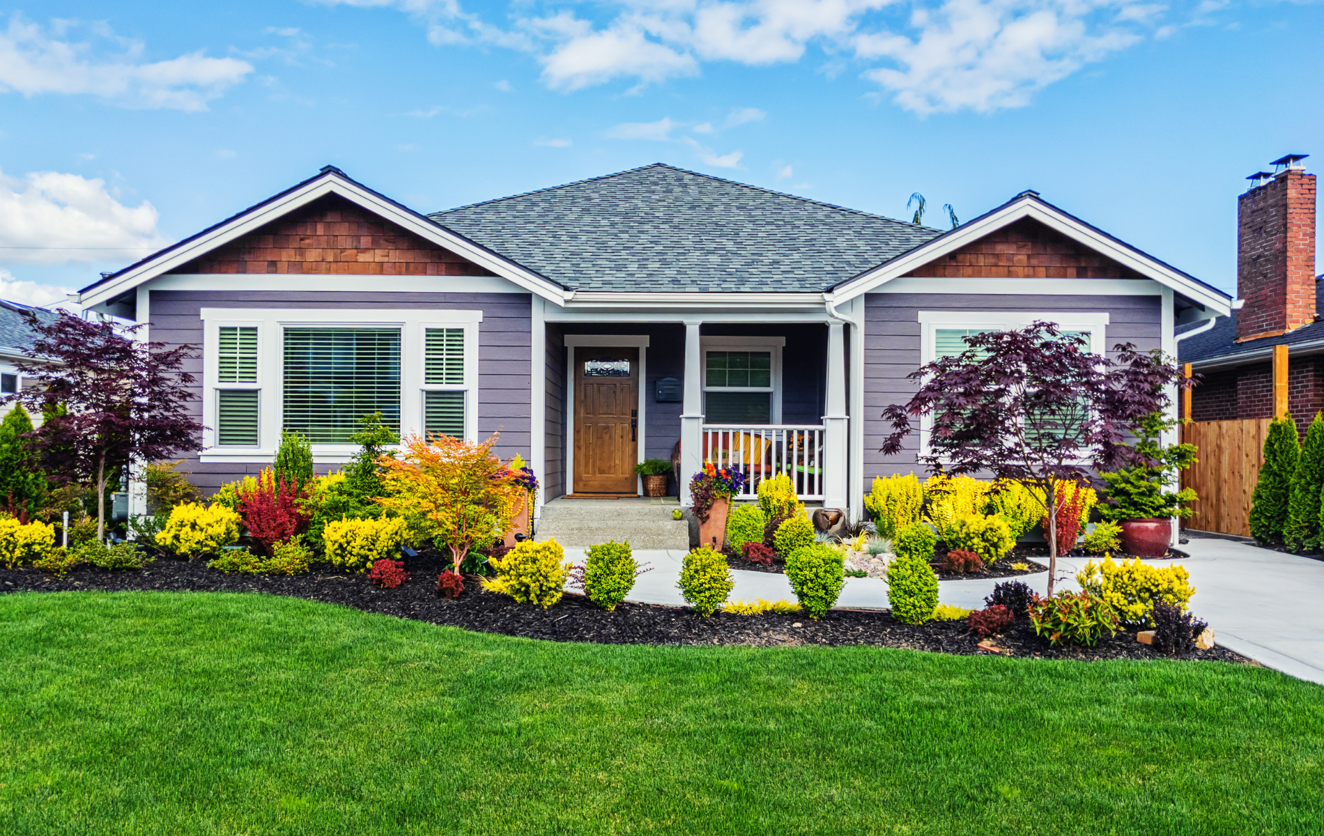 A purple house with a lush green lawn in front of it.