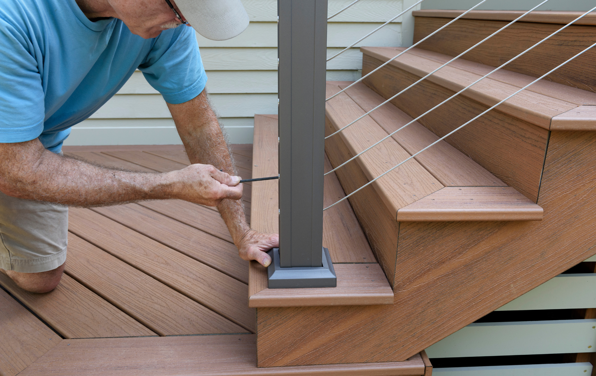 A man is installing a railing on a wooden deck.