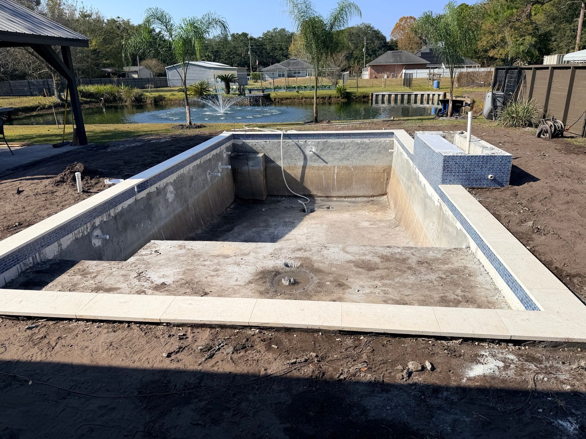 Empty rectangular pool under construction with blue tile accents.