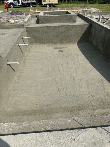 Wooden forms for a concrete foundation on a construction site next to a house under blue sky.