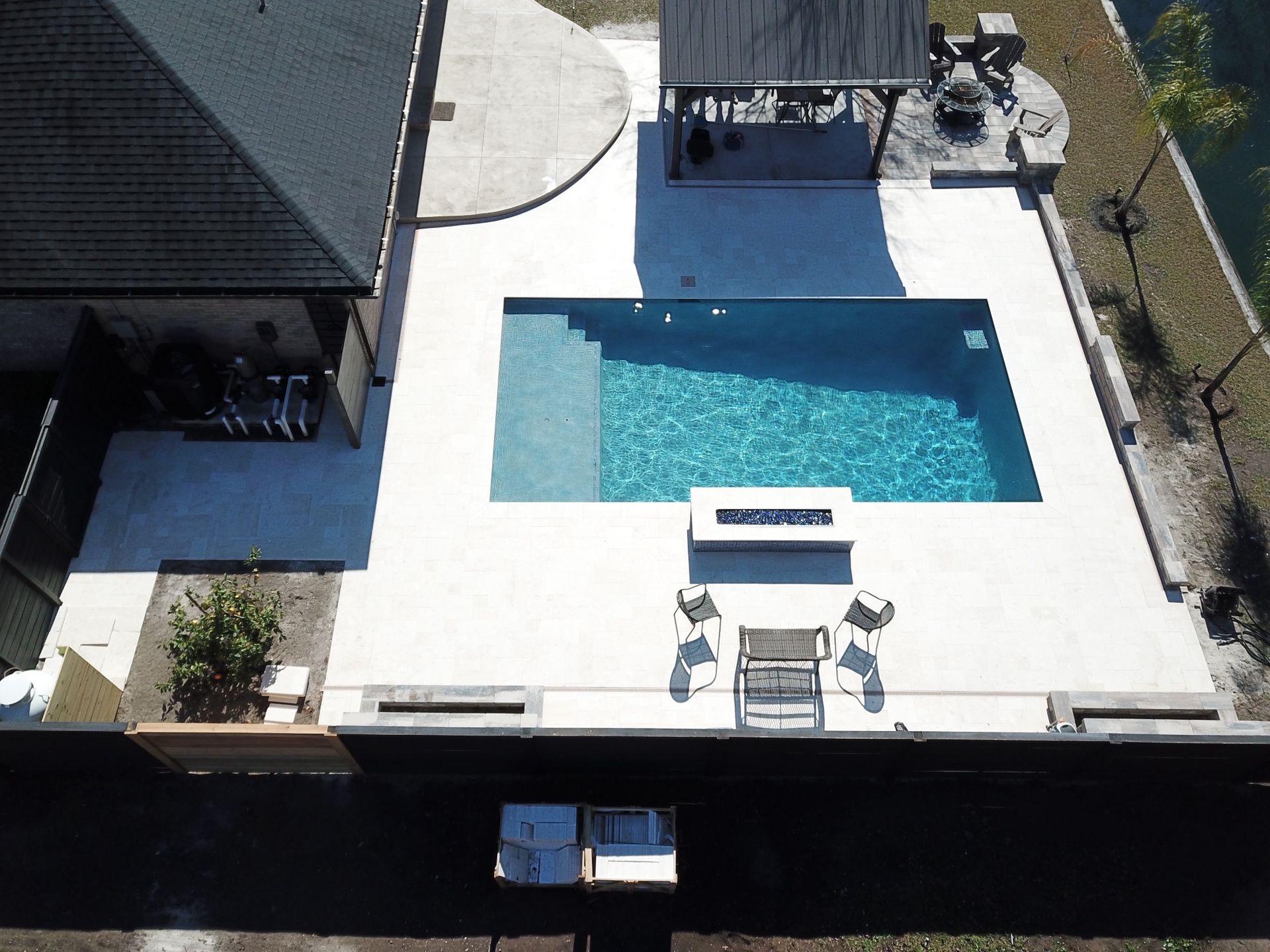 Overhead view of a rectangular pool with patio, seating, and a covered gazebo.