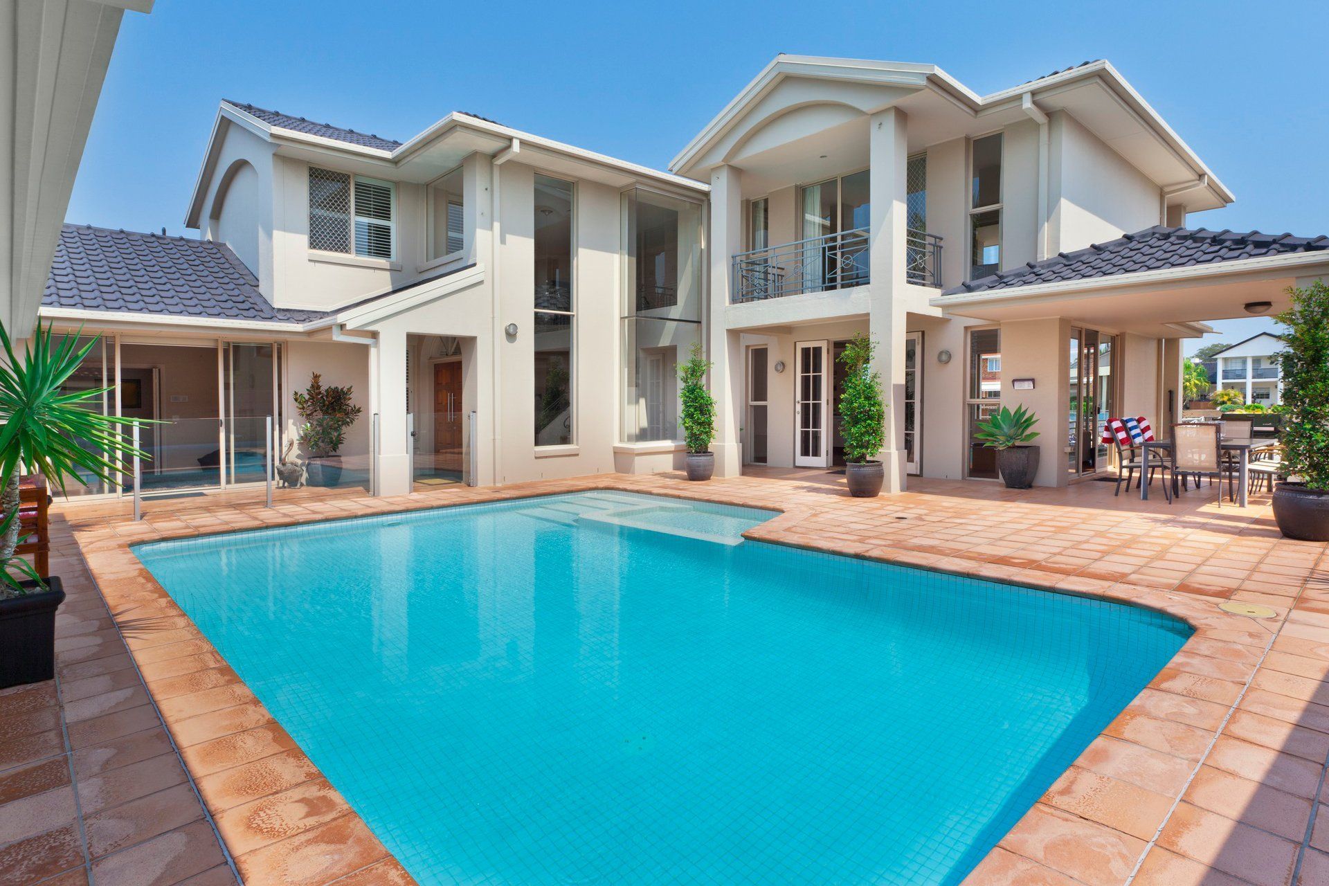 Two-story house with blue swimming pool and patio. Exterior shot, sunny day. Two-story house with blue swimming pool and patio. Exterior shot, sunny day.