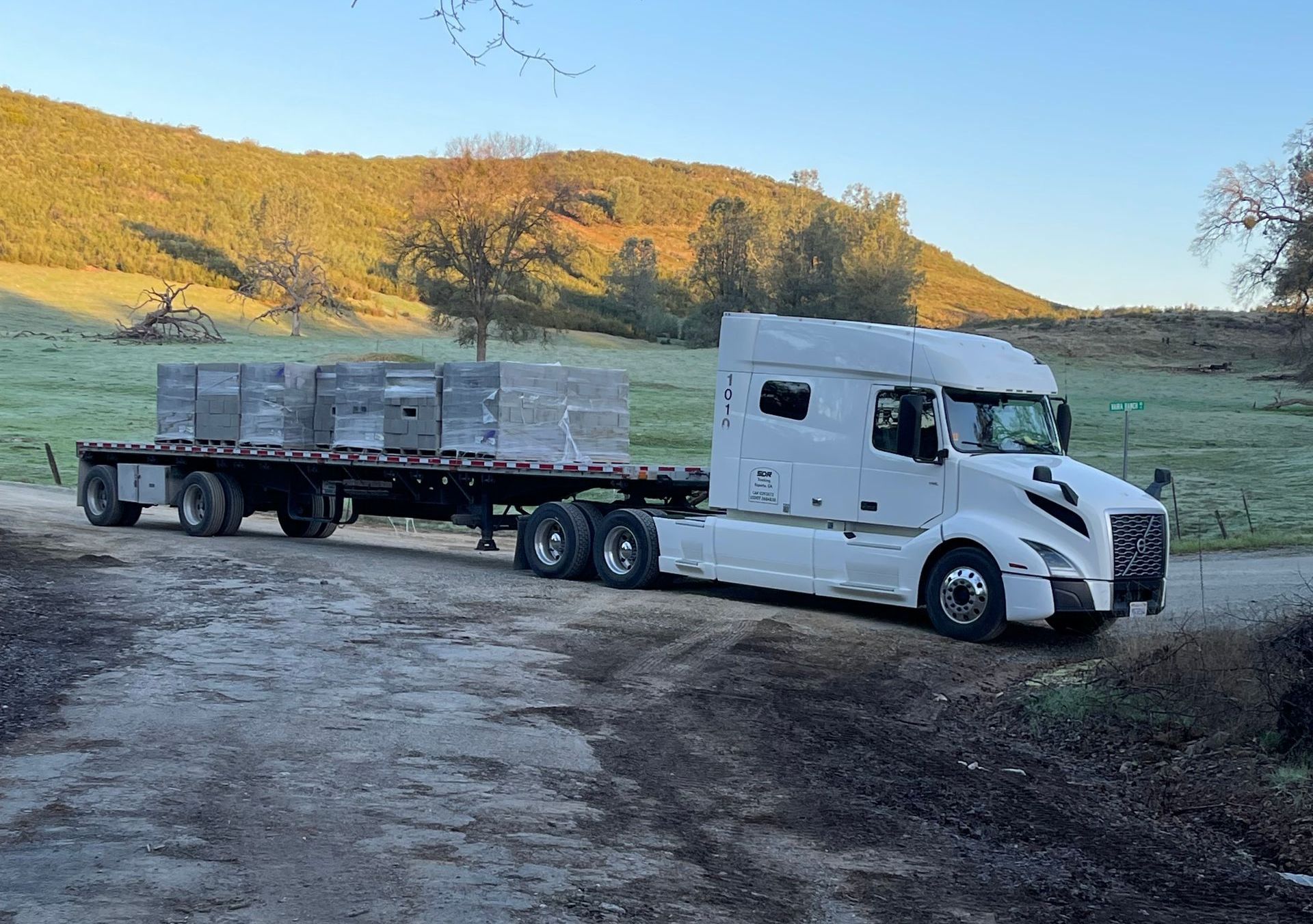 A white semi truck is driving down a dirt road.