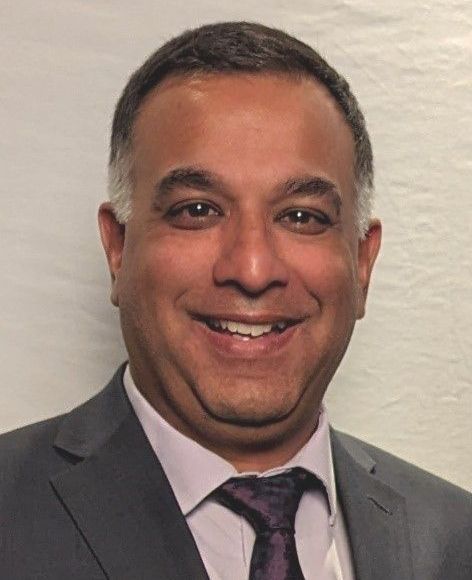 A man in a suit and tie is smiling for the camera.
