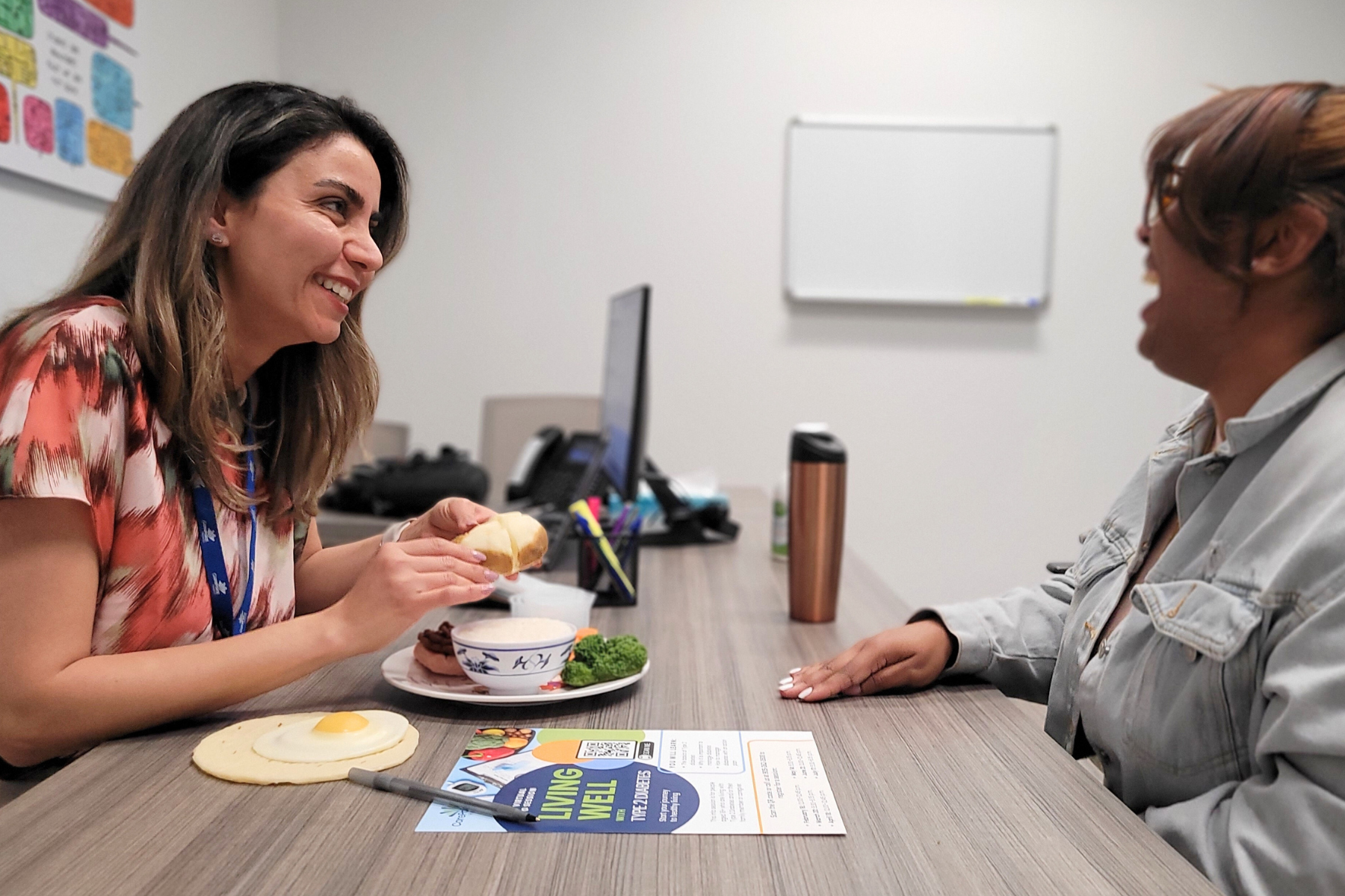 A dietitian smiling at a patient and showing a food demo