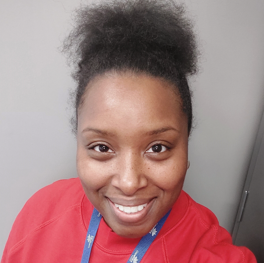 A woman in a red shirt is smiling for the camera.