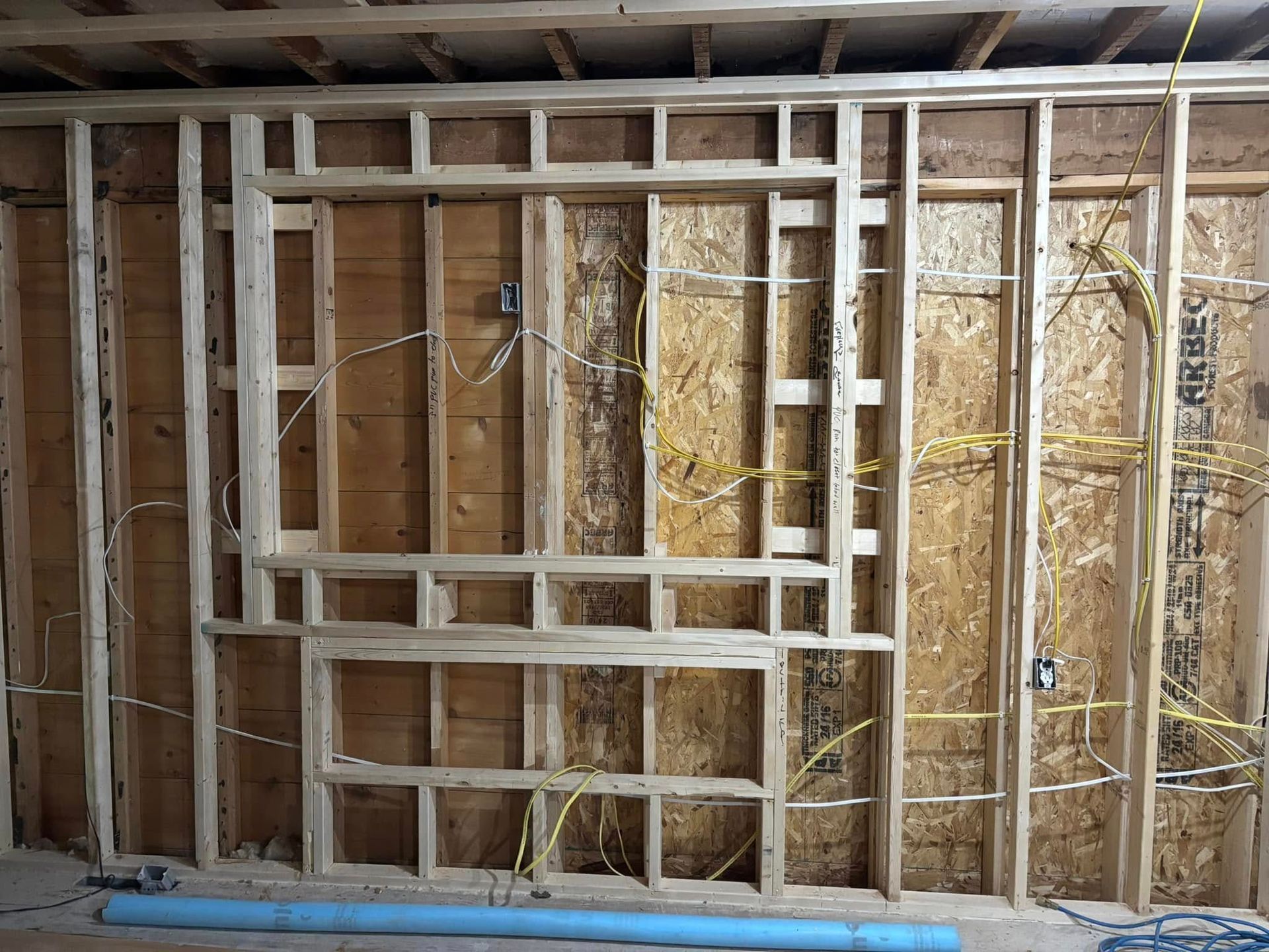 Wooden wall framing with electrical wires, possibly for a fireplace and television installation.