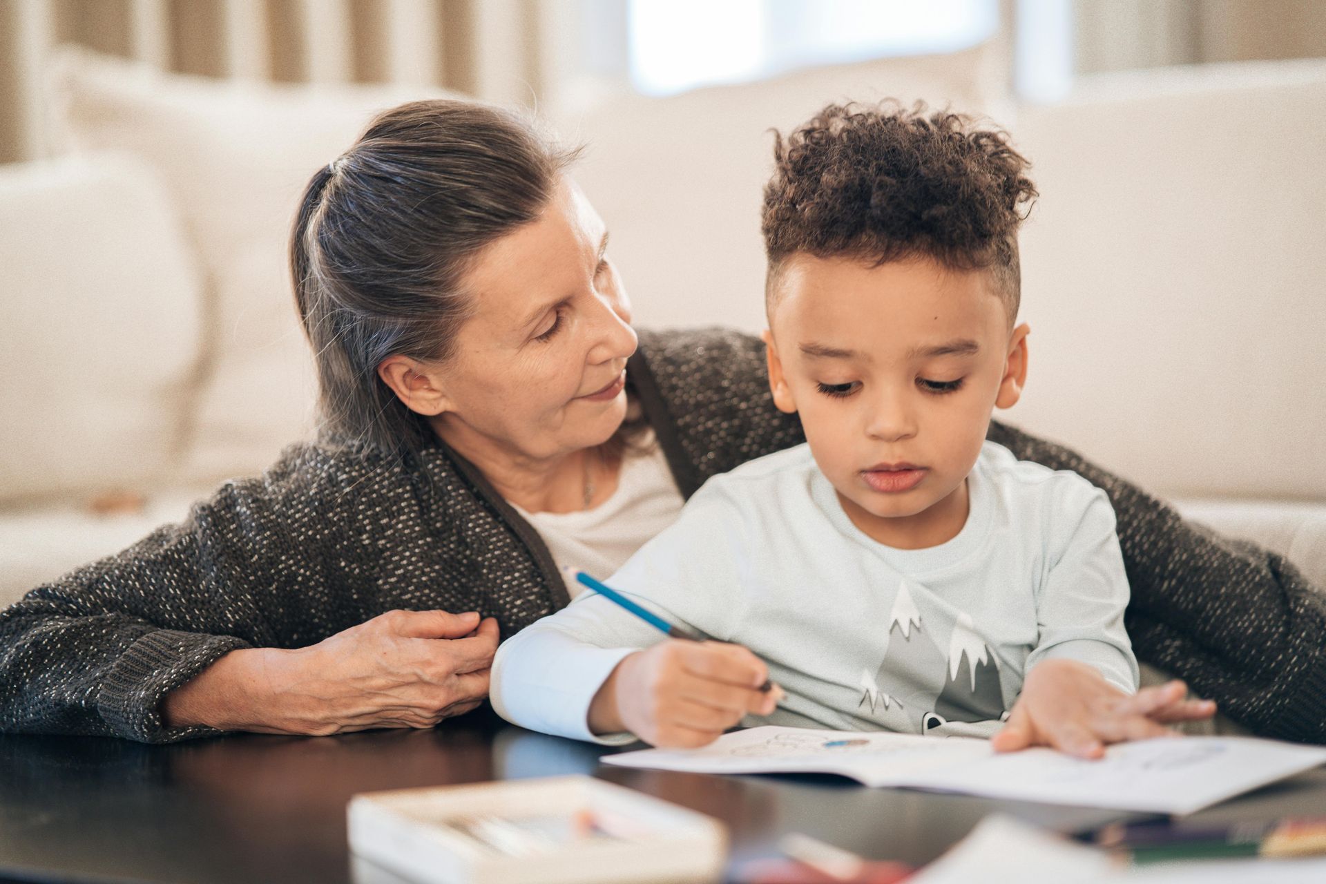 An elderly woman is helping a young boy with his homework.