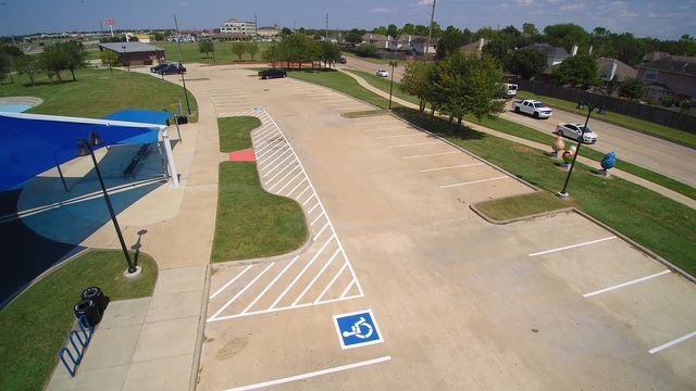 An aerial view of a parking lot featuring a designated handicap-accessible space and striped loading zone.