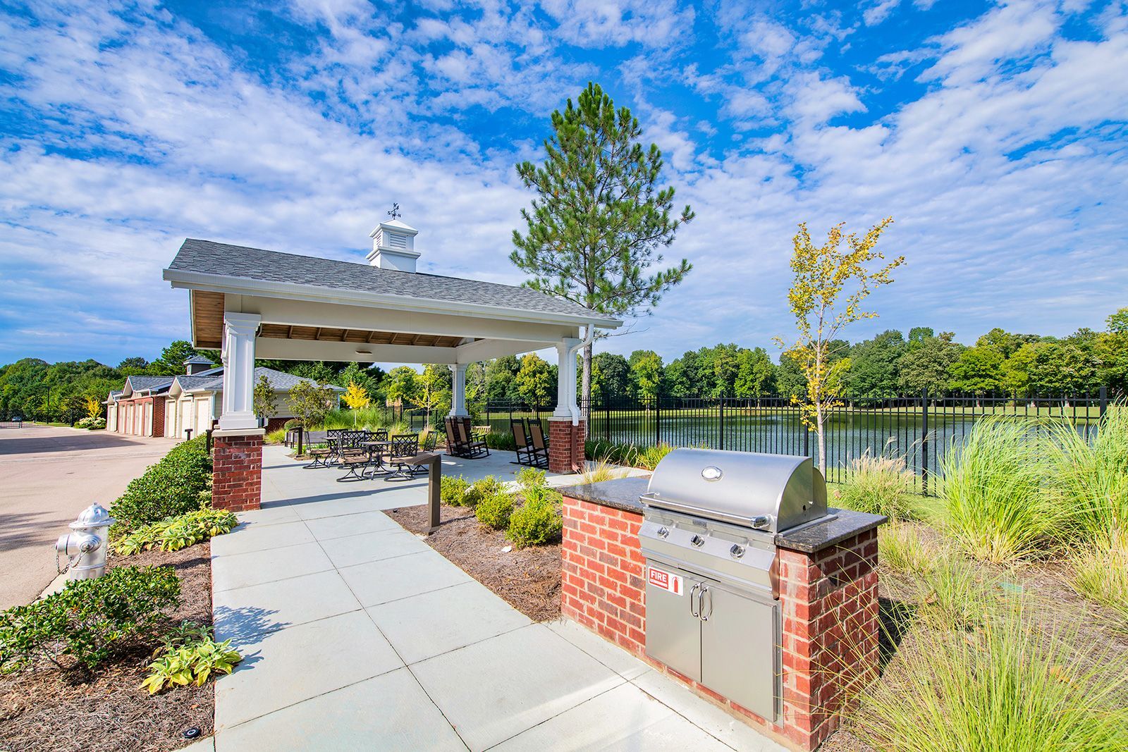 Outdoor pavilion with grill by a lake on a sunny day.