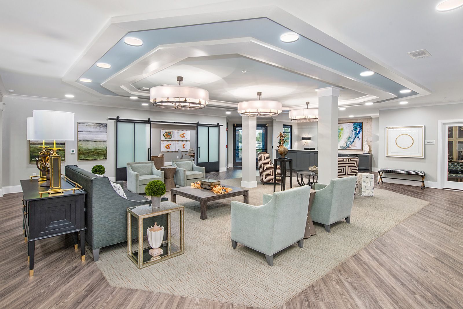 Spacious light-filled lounge with couches, chairs, and decorative accents. Features light blue accents and hardwood floors.