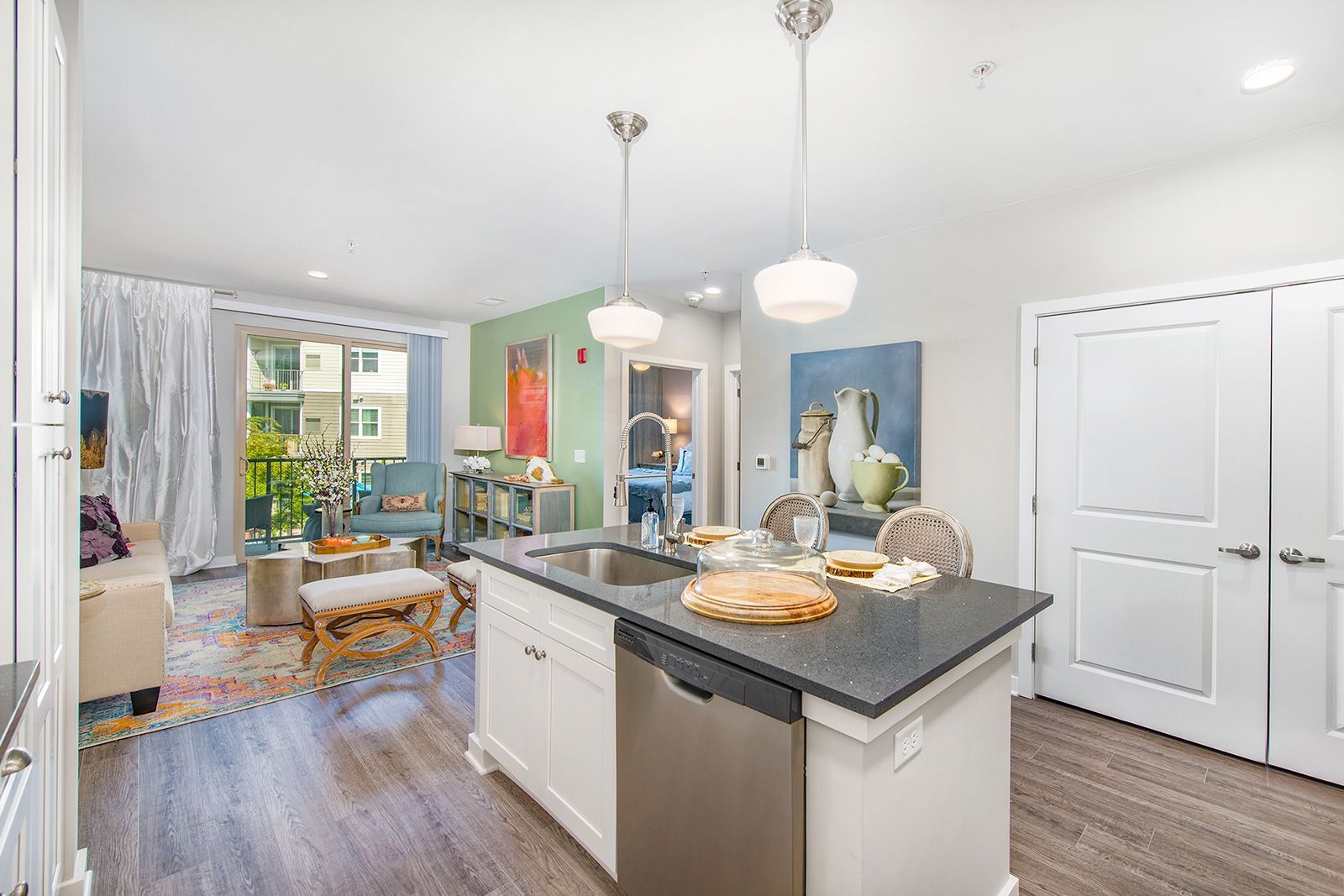 Open-concept kitchen with island, stainless steel appliances, and dining area with a view of a balcony.