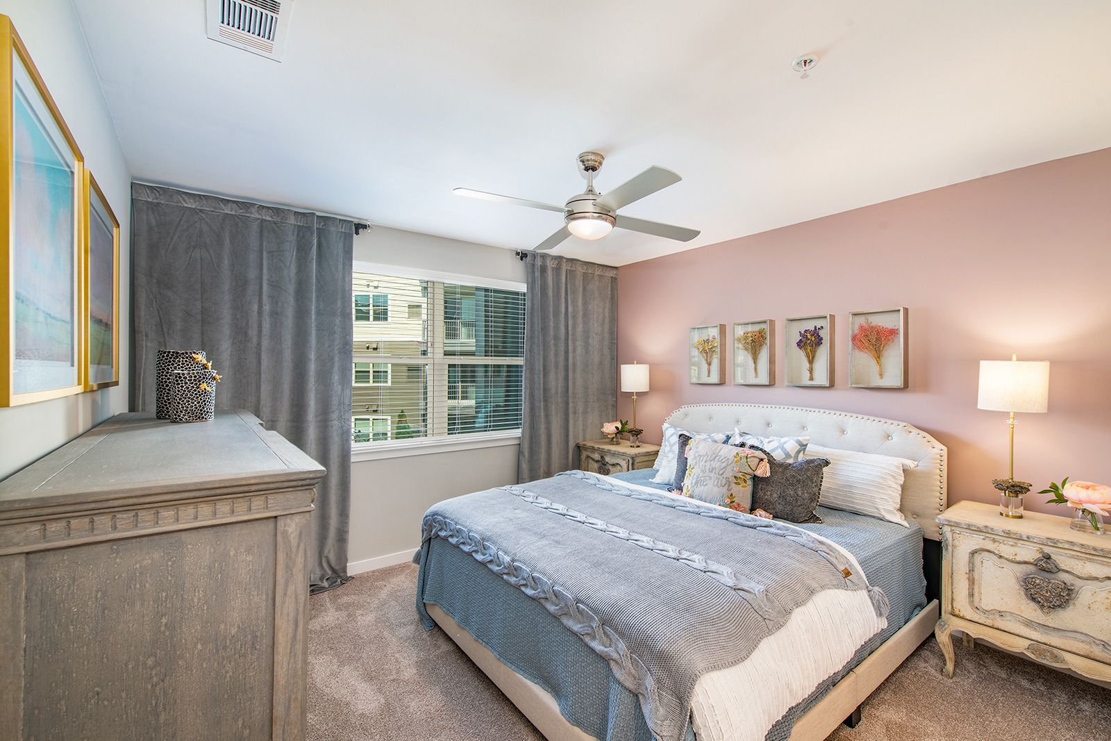 Bedroom with pink wall, double bed, gray dresser, and window with gray curtains.