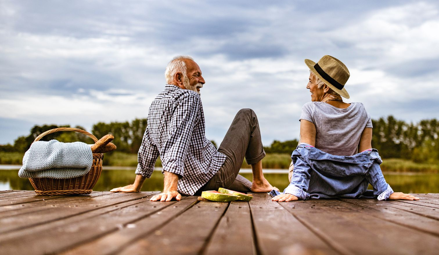 Outdoor patio with fire pit and seating; pool and sunset background.