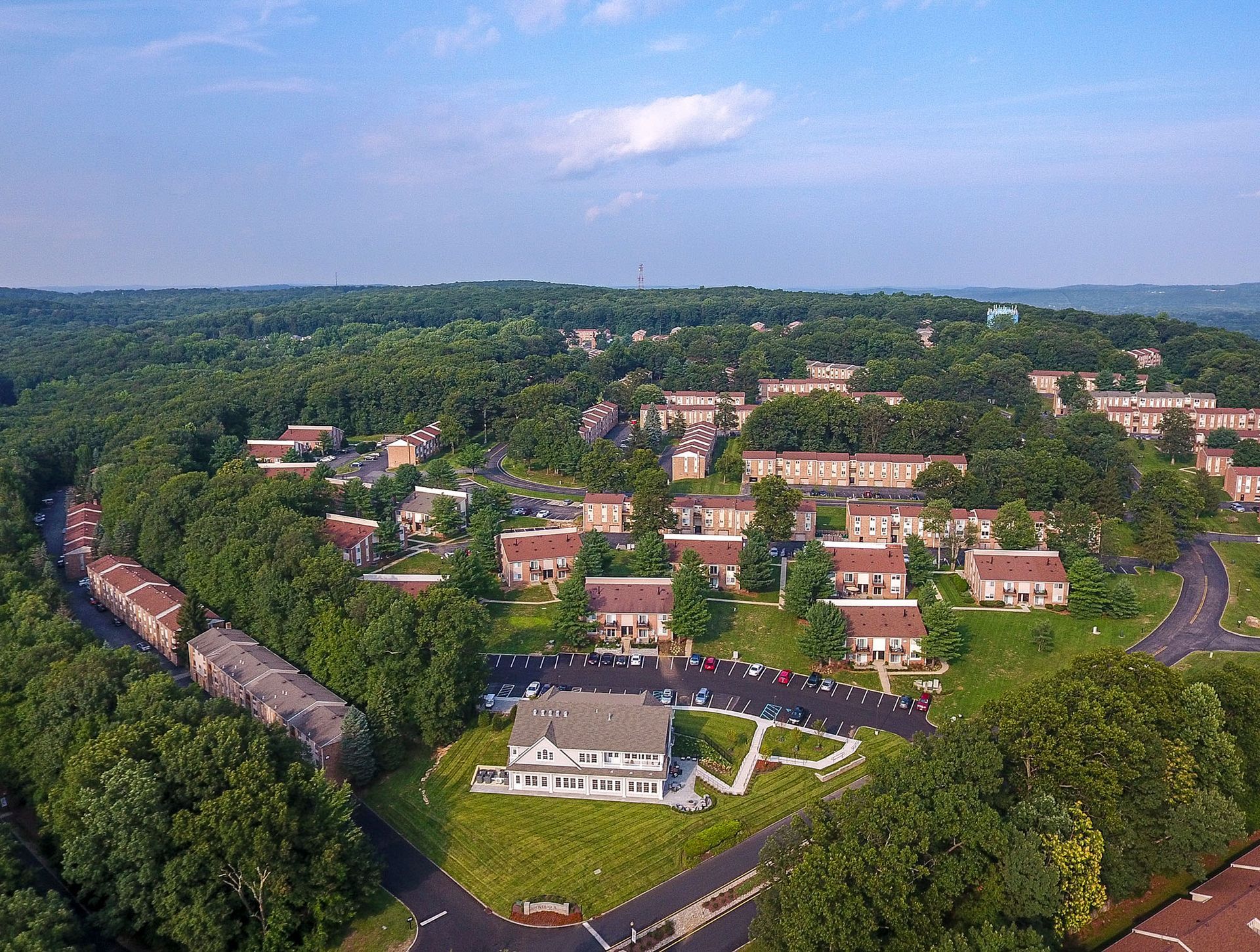 Aerial view of a large apartment community with brick buildings, roads, and green trees.