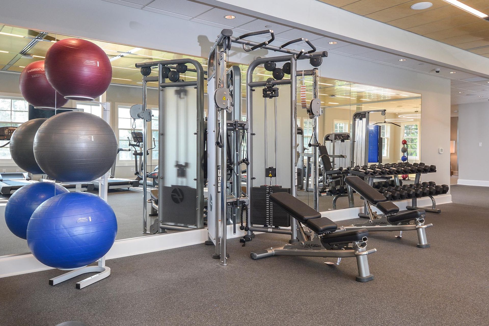 Interior fitness center with weight machines, benches, dumbbells, and large exercise balls.