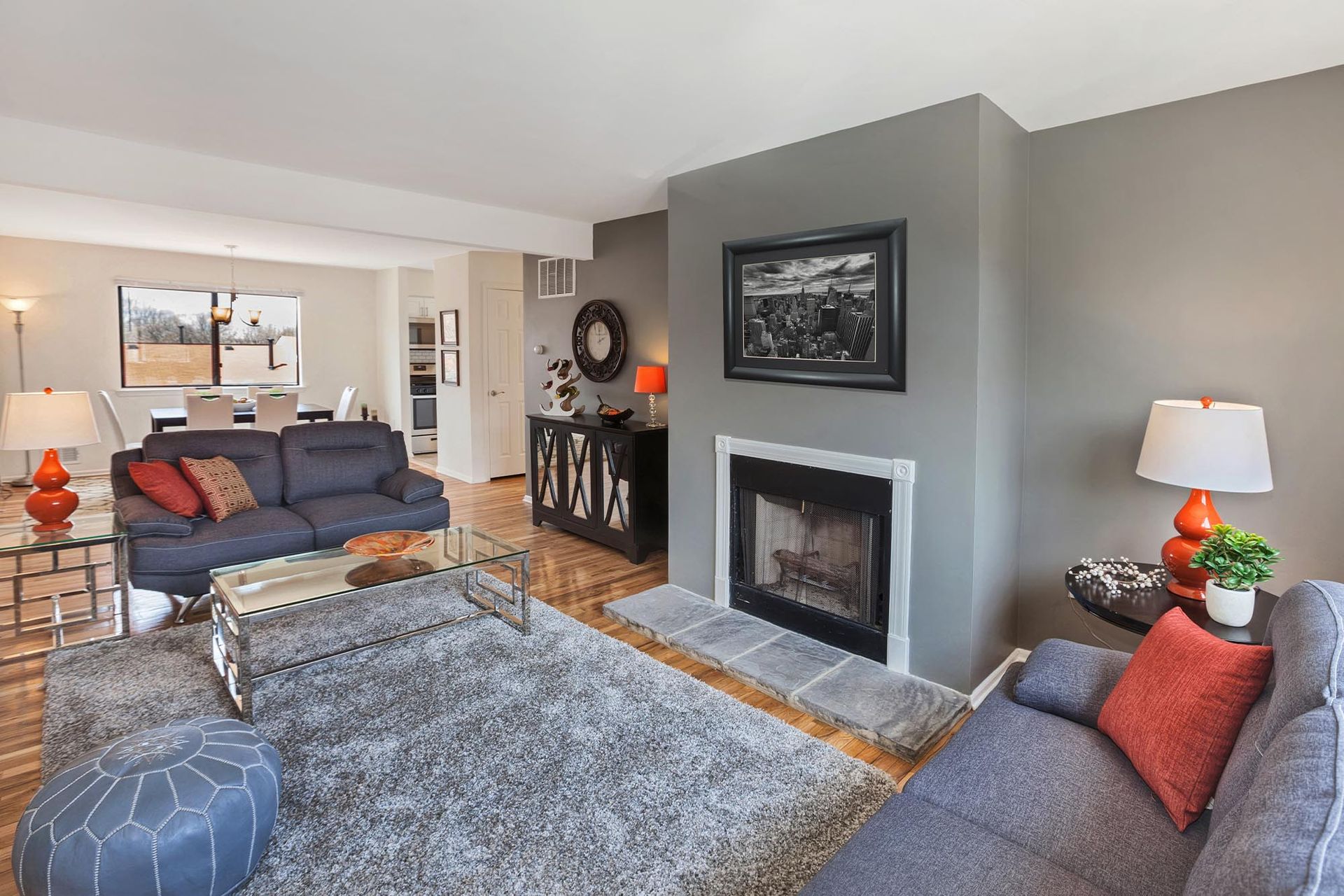 Living room with gray walls, blue sofas, a glass coffee table, and a fireplace.