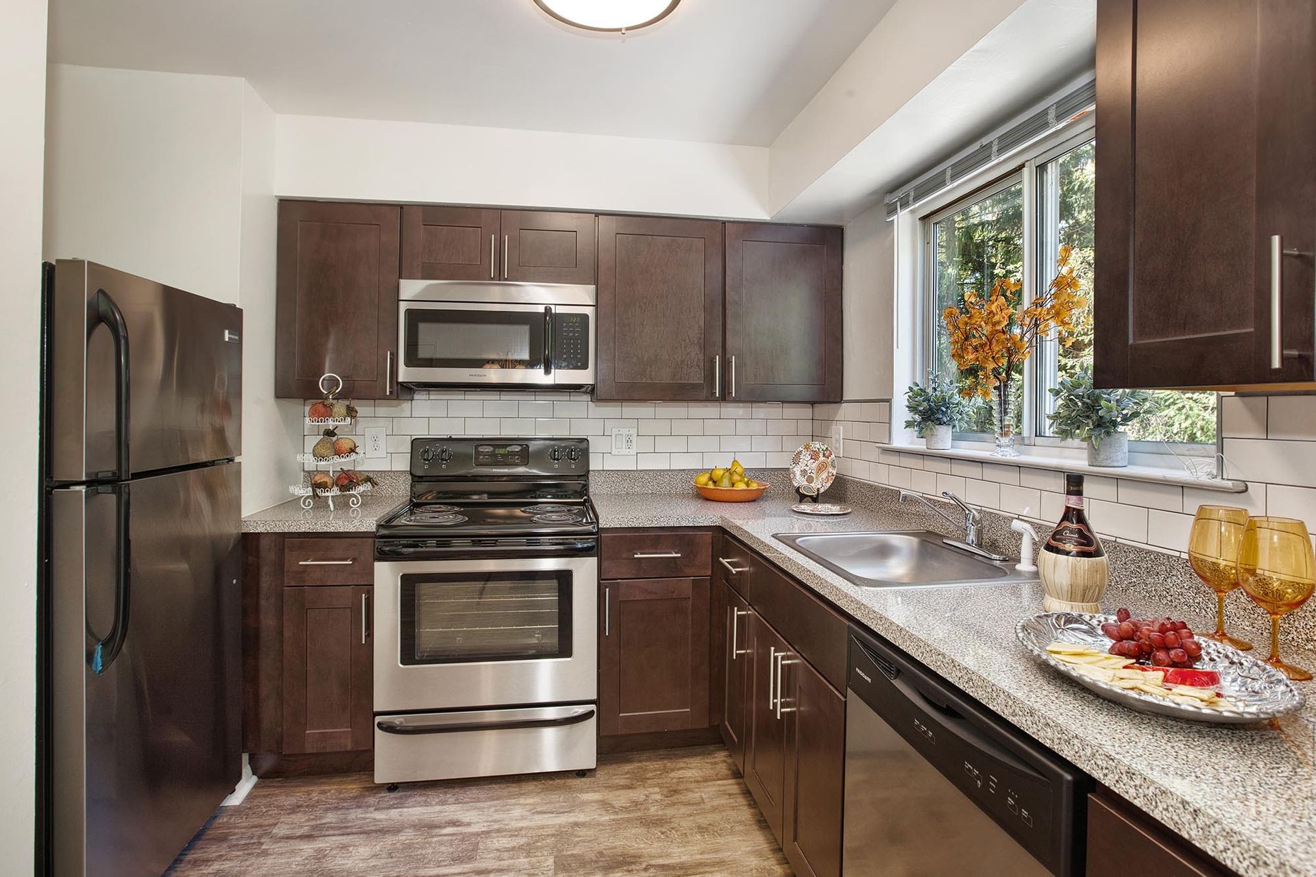 Modern kitchen with dark wood cabinets, stainless steel appliances, and a window over the sink.