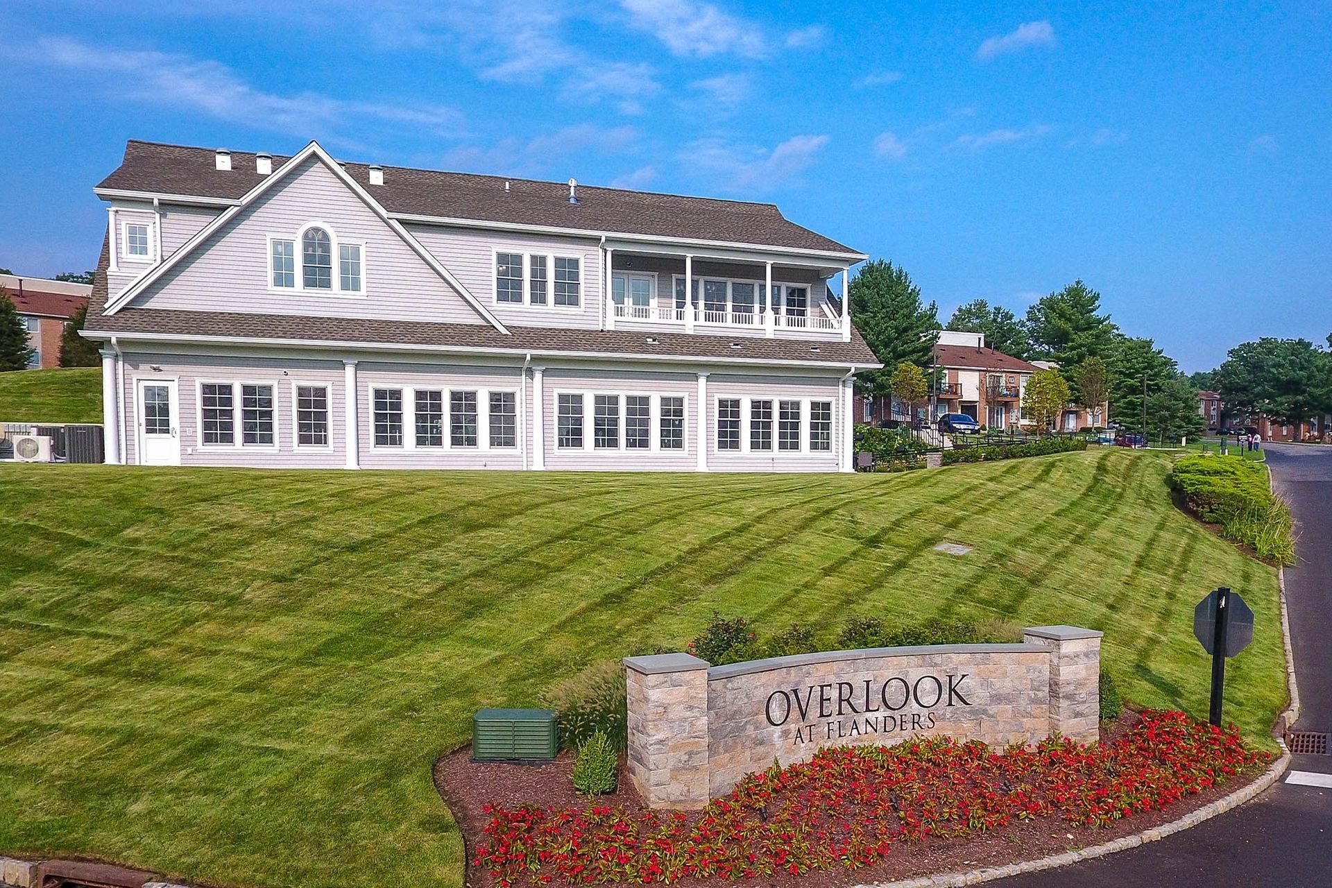 Exterior view of the Overlook at Flanders apartment community with a manicured lawn and entry sign.