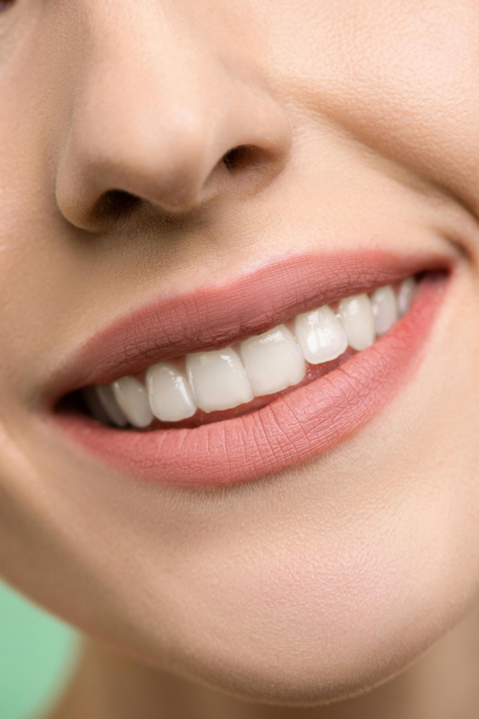 A close up of a woman 's smile with white teeth and pink lips.