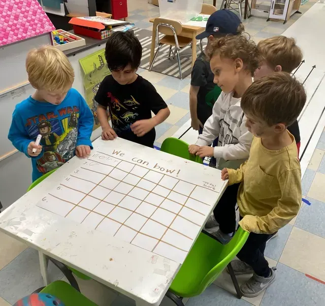 Children gather around a whiteboard, writing 