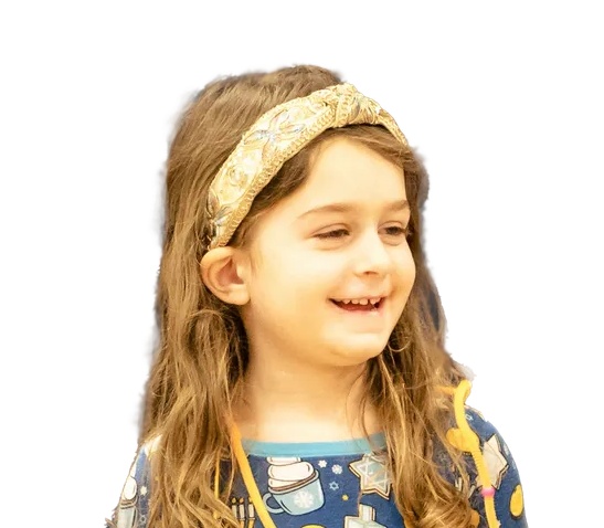 Woman with curly brown hair, glasses, and a blue shirt, smiling at the camera.