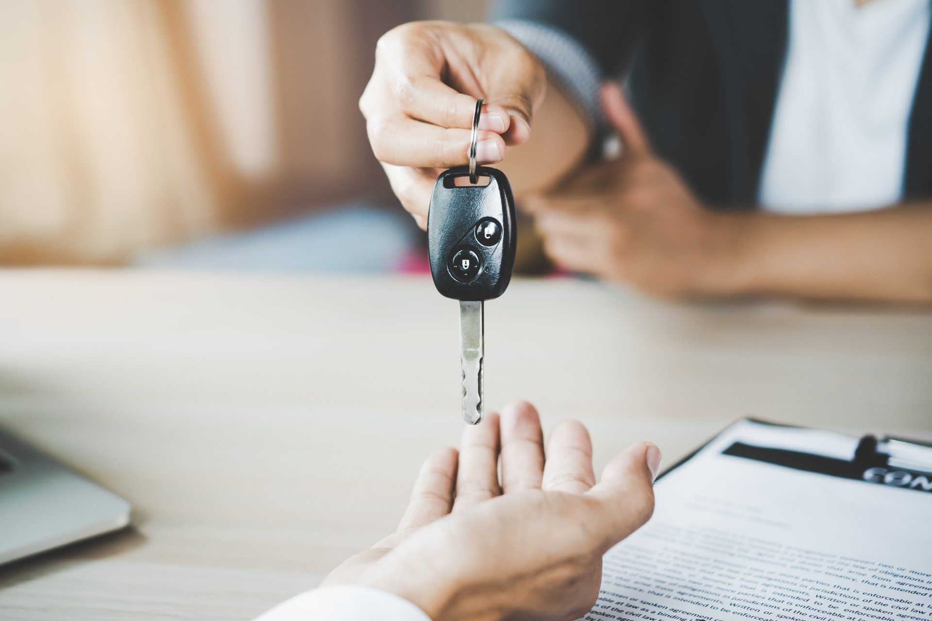 Person handing keys to new car owner