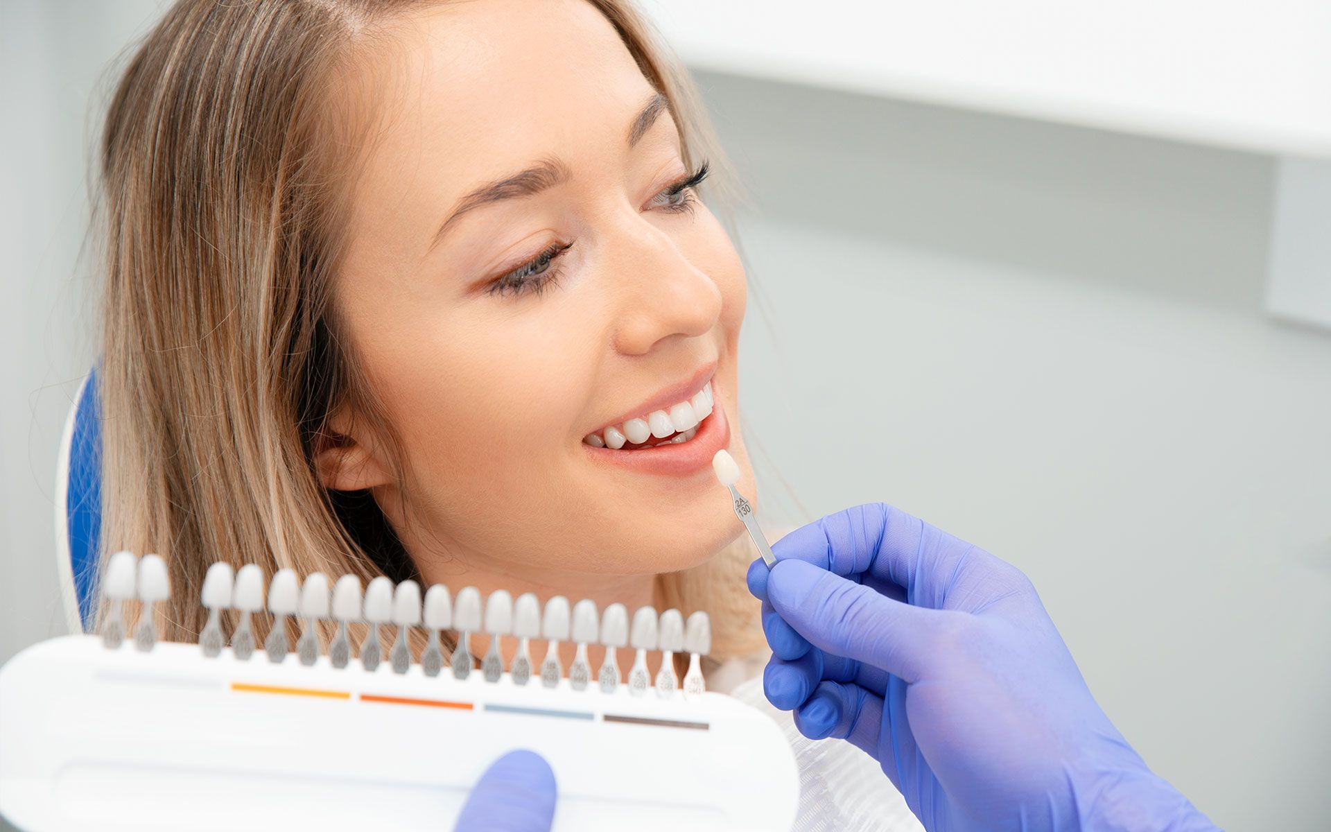 A woman is sitting in a dental chair while a dentist examines her teeth.