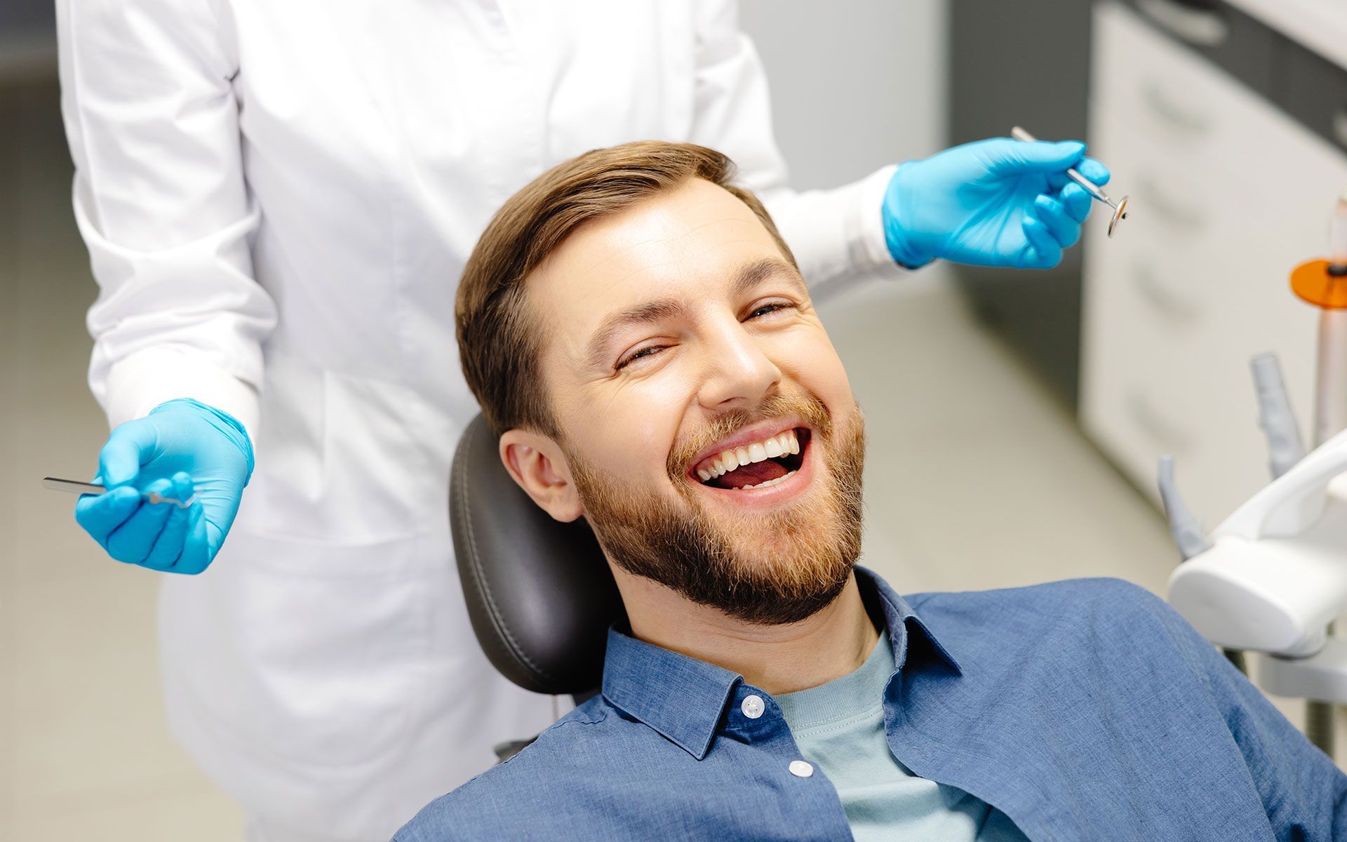 A man is smiling while sitting in a dental chair.