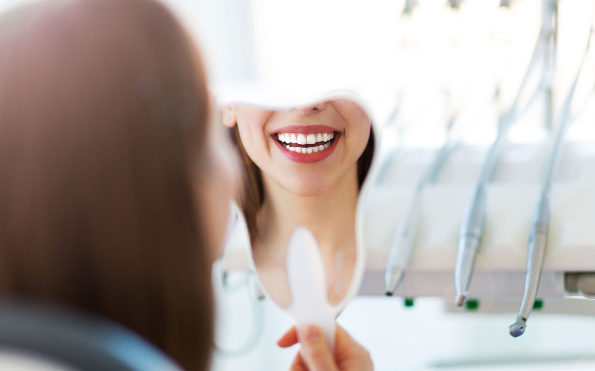 A woman is looking at her smile in a mirror.