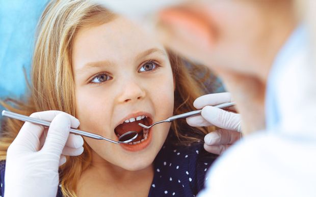 A little girl is getting her teeth examined by a dentist.