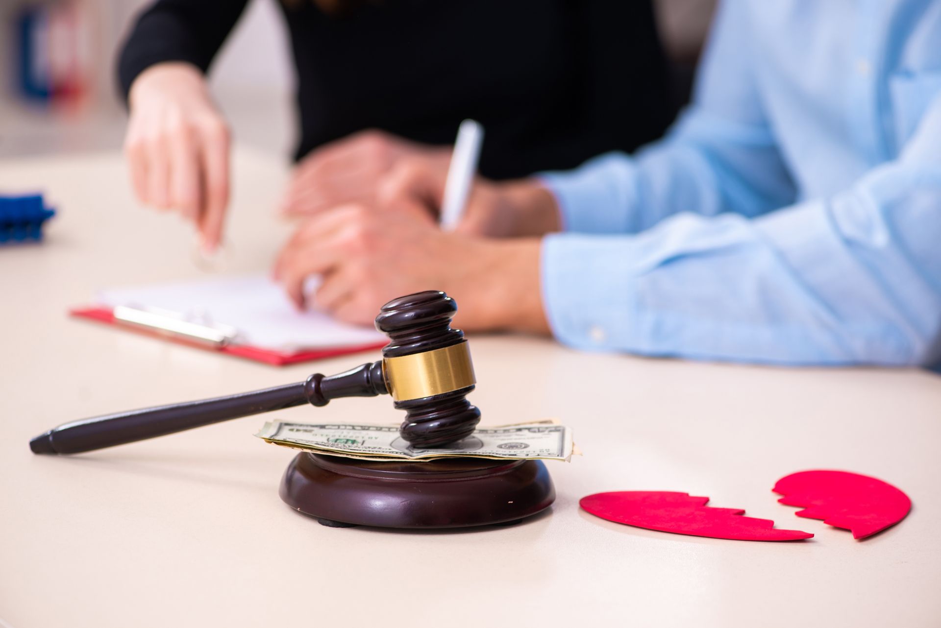 A Couple is Sitting at a Table With a Judge 's Gavel and a Broken Heart