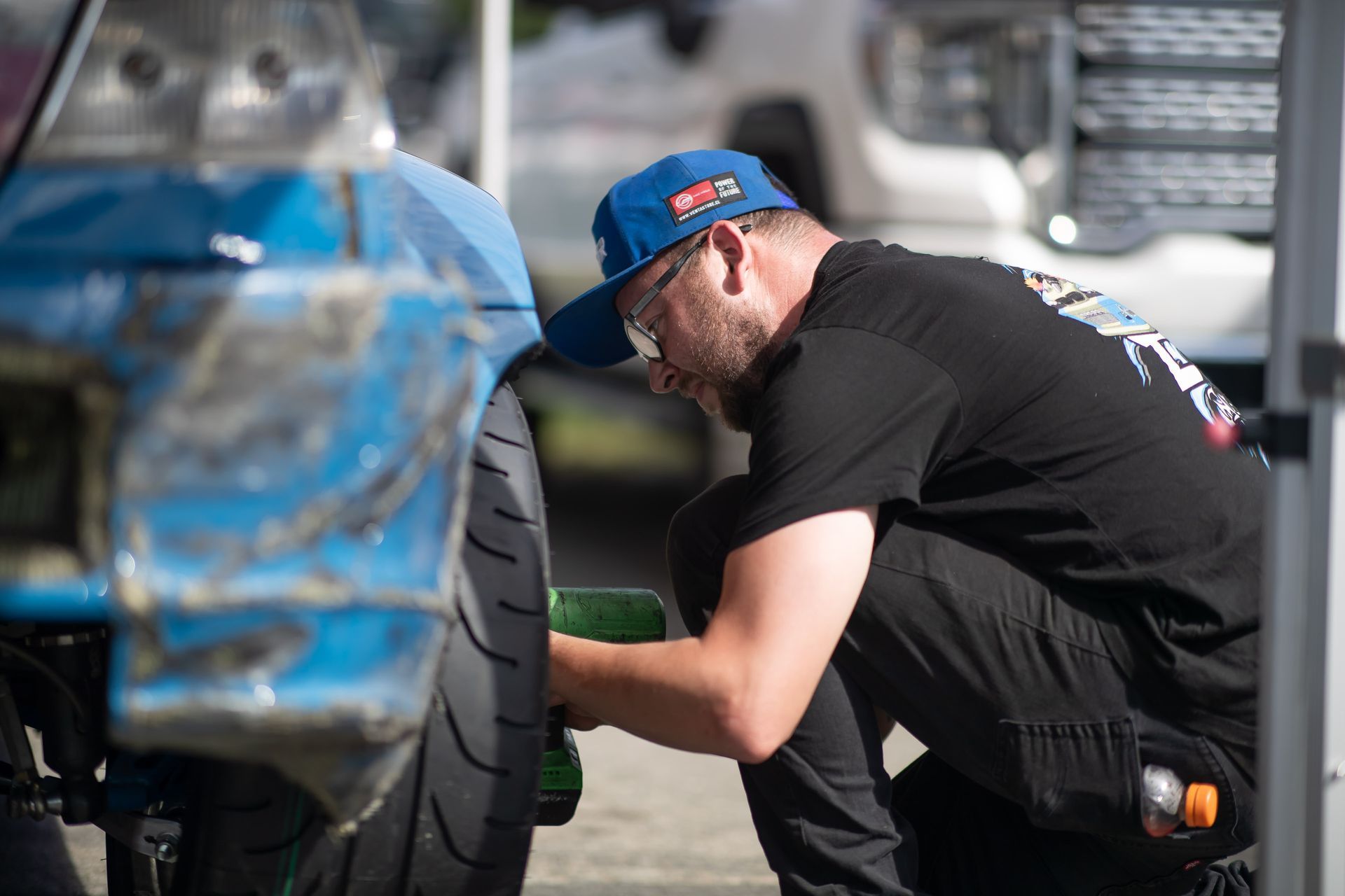 A man in a blue hat is working on a tire on a motorcycle.