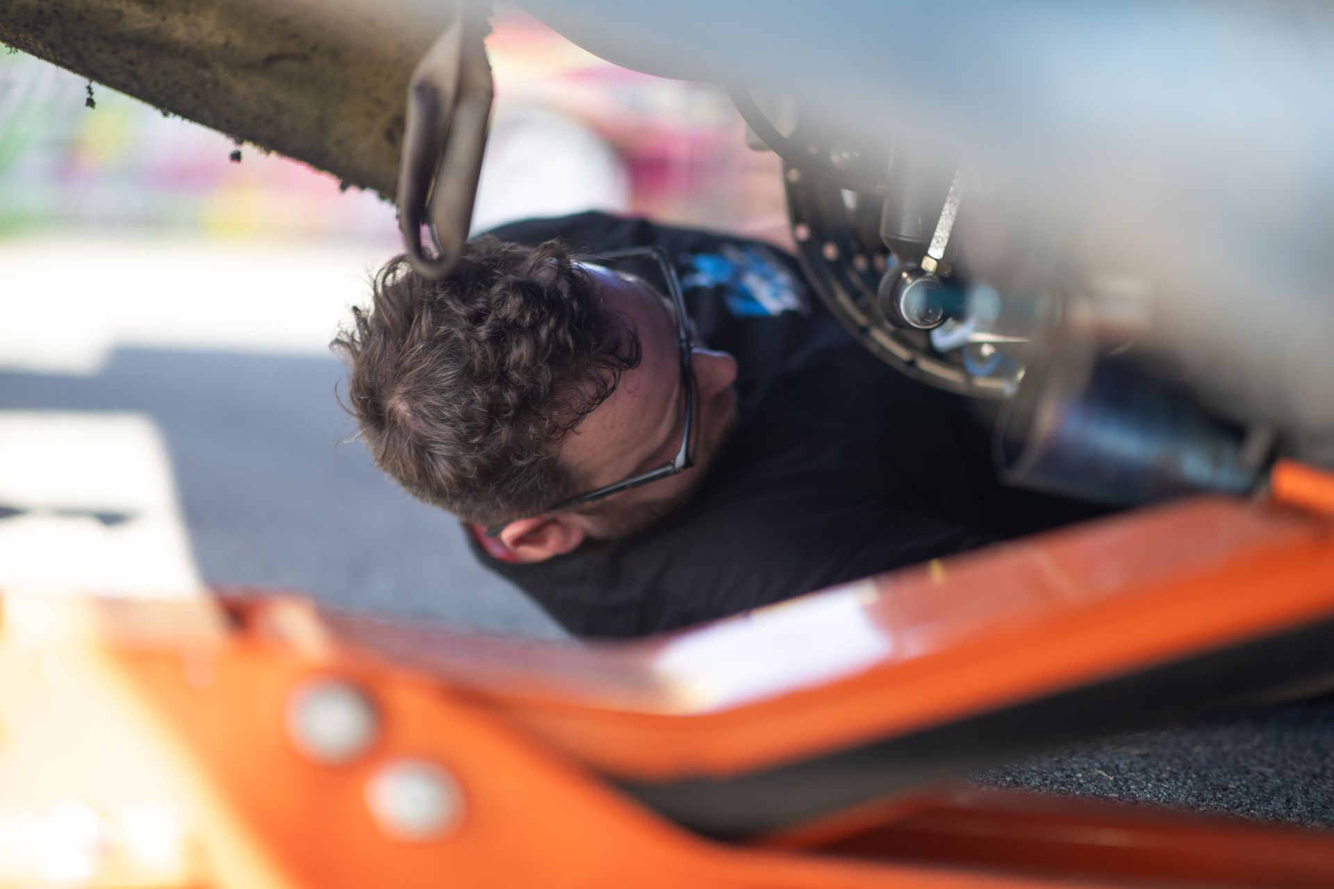 Mike Klamm is laying on the ground under a car.
