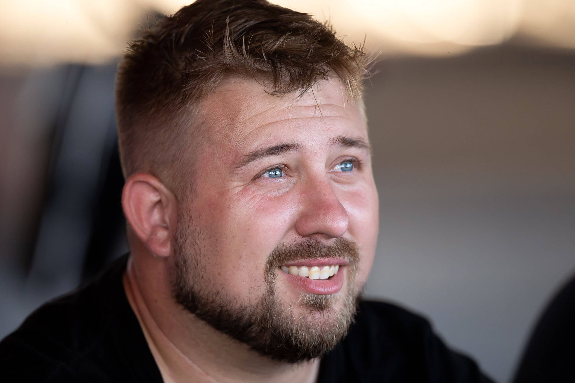 A man with a beard and blue eyes is smiling.