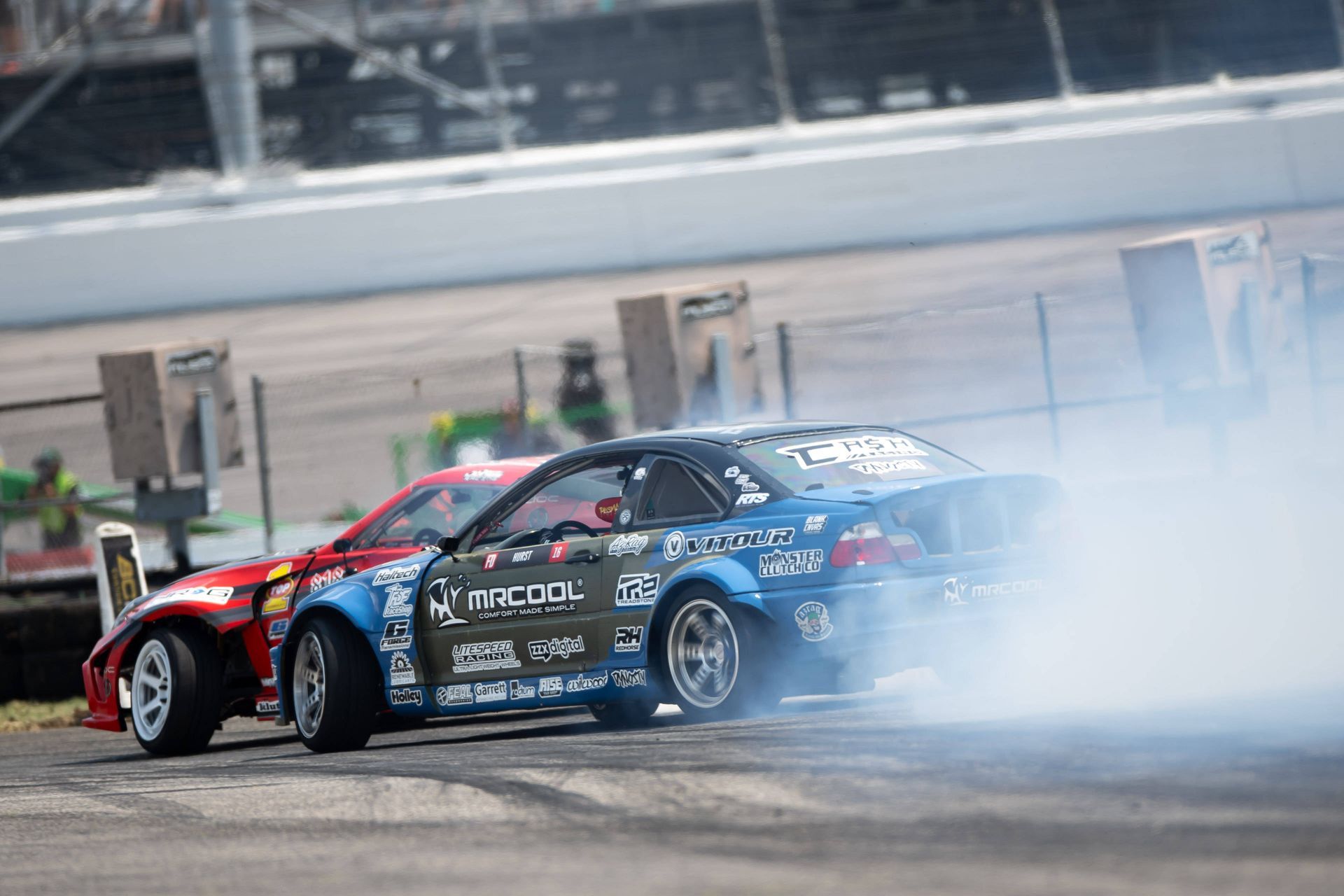 Two racing cars are drifting on a race track.