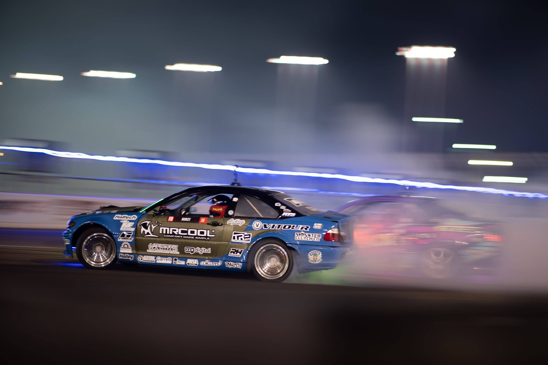 The Cash Racing Mr. Cool BMW blue race car is drifting on a race track.