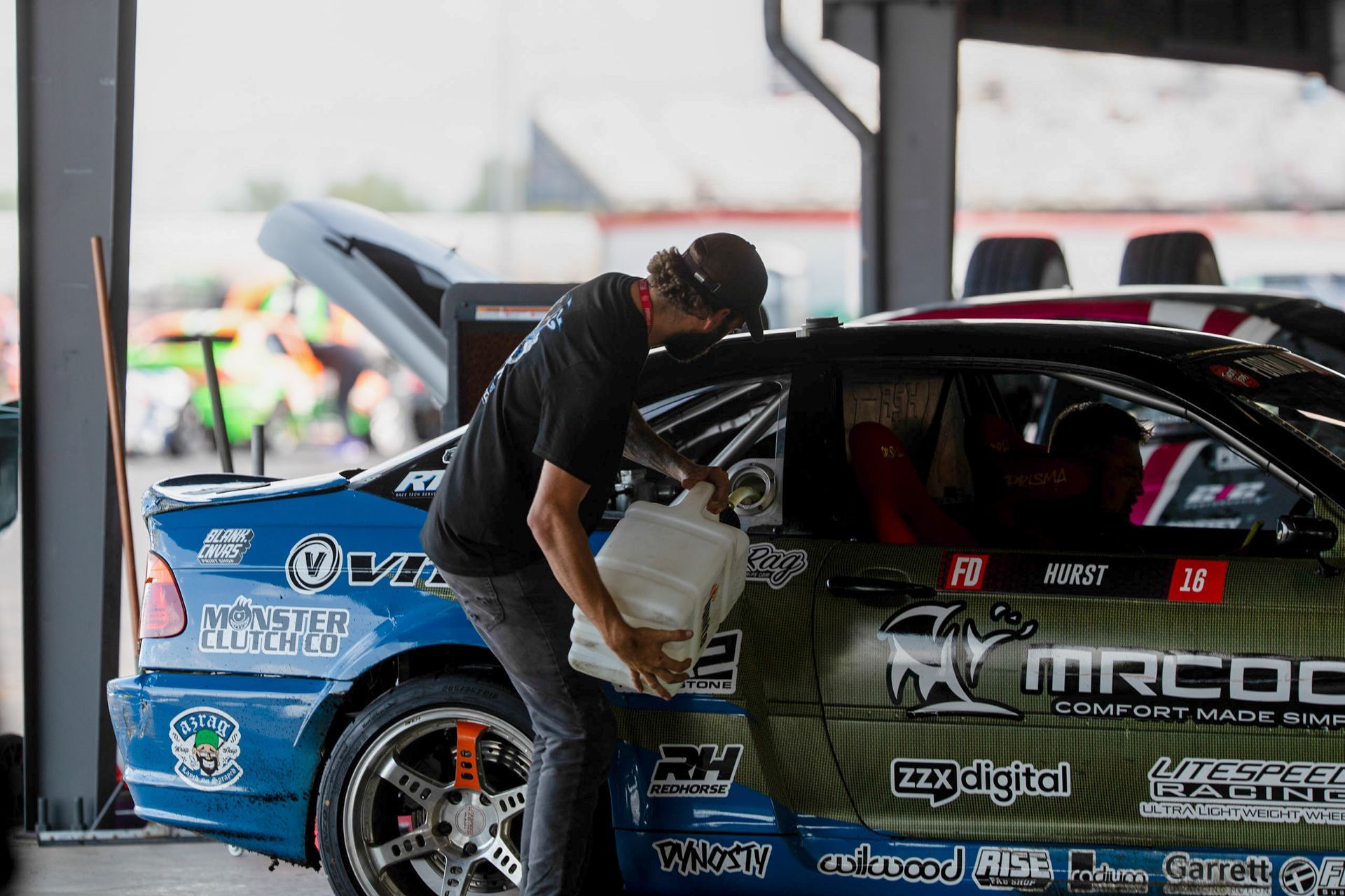 A man is loading fuel into a race car.