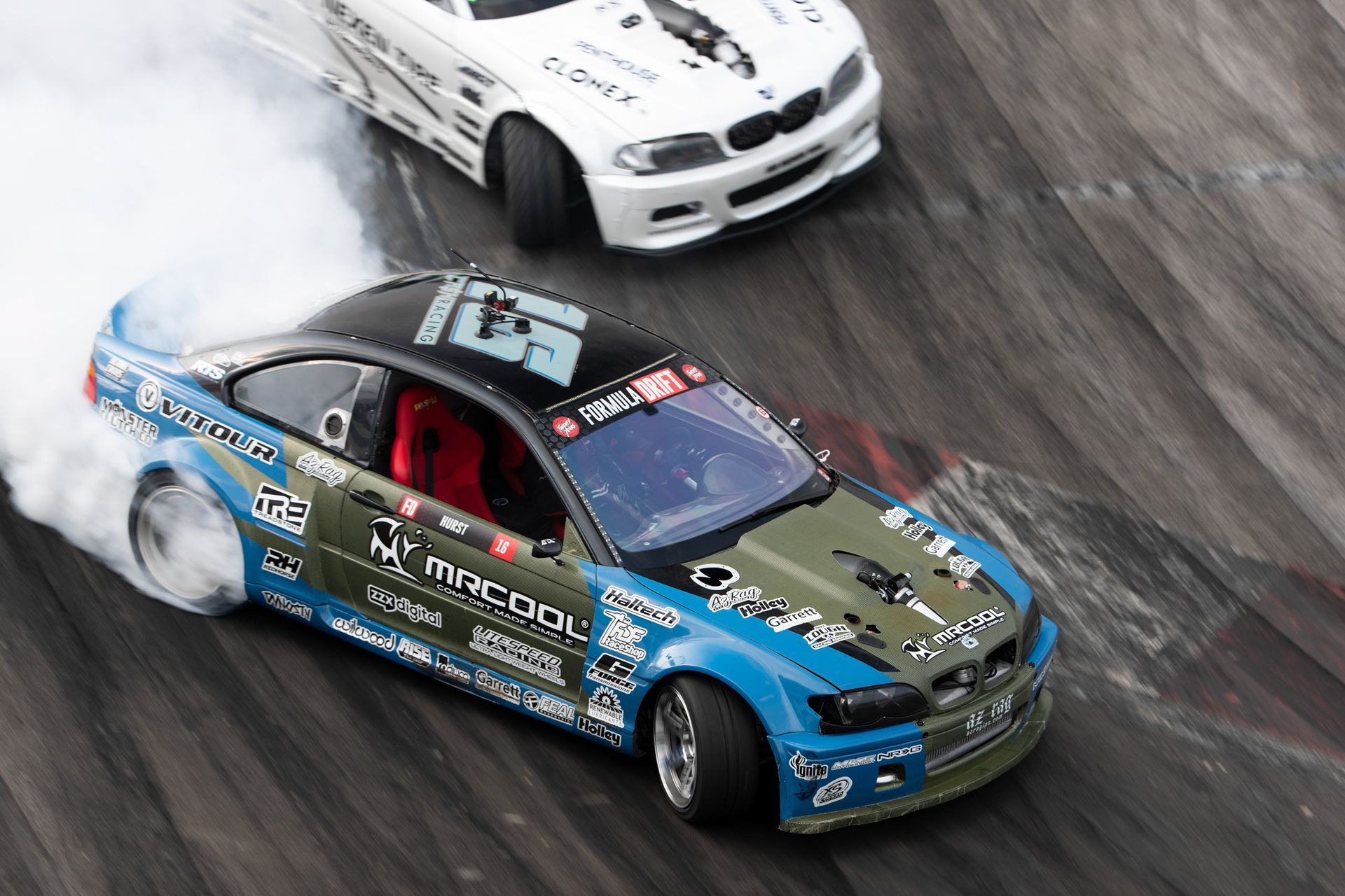 Two racing cars are drifting on a track.