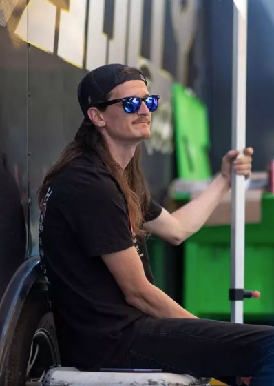 A man with long hair wearing sunglasses and a hat