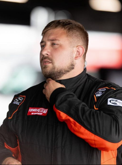 Jonathan Hurst with a beard is wearing a black and orange jacket.